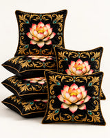 Black cushion covers featuring pink and gold lotus flowers, ornate golden scrollwork, turquoise accents and gold piping.