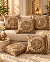 Taupe brown cushion covers featuring intricate gold floral medallions and Greek-key borders arranged on a cream sofa.